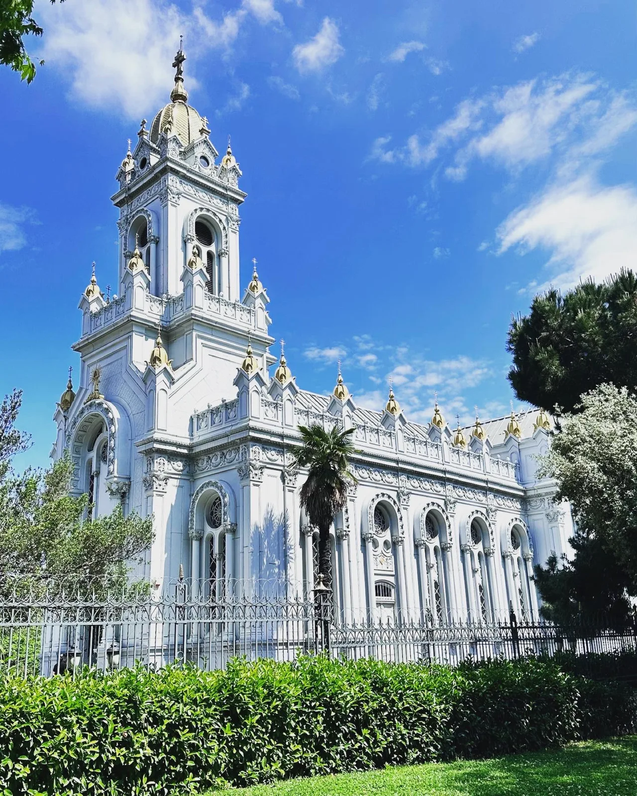 Fachada blanca y campanario de la iglesia de San Esteban en Balat, entre árboles.