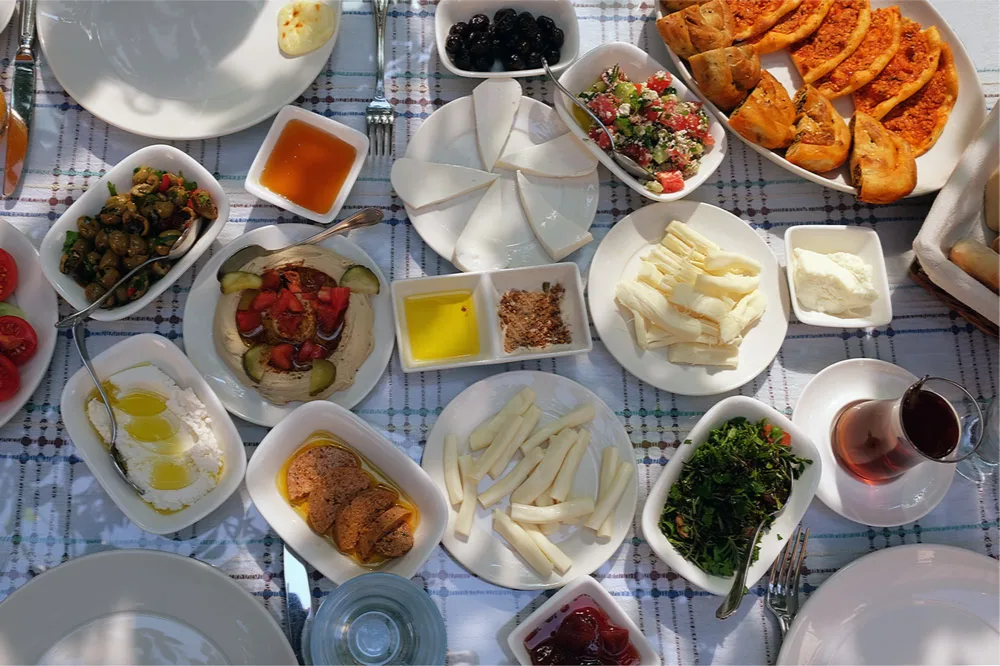 Mesa de desayuno turco con queso, aceitunas, pan y pequeños platos para compartir.