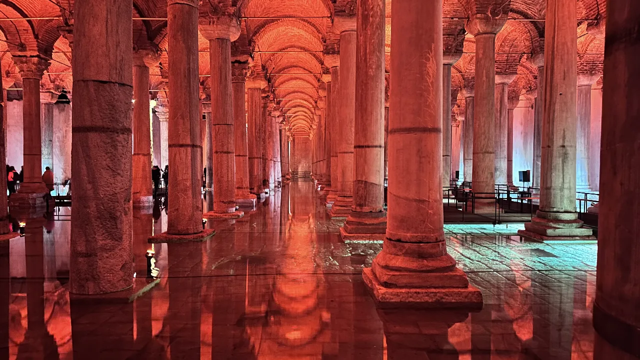 Columnas de la Cisterna Basílica iluminadas con tonos cálidos y reflejadas en el agua.
